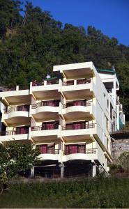 a white building with balconies on the side of a mountain at Green Roof Hotel in Nainital
