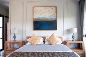 a bedroom with a bed with two tables and a painting at Casa Narrow Villa in Nembrala