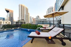 balcón con piscina, sillas y sombrilla en Syama Suite Sukhumvit 20, en Bangkok
