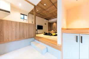a kitchen with wooden cabinets and a living room at MUSUBI HOTEL MACHIYA Naraya-machi 2 in Fukuoka