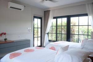 two white beds in a room with windows at Casa Narrow Villa in Nembrala