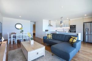 a living room with a blue couch and a kitchen at Sandbox Apartments in Gold Coast