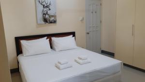a bedroom with a white bed with two white pillows at Tulip Apartment in Ormoc