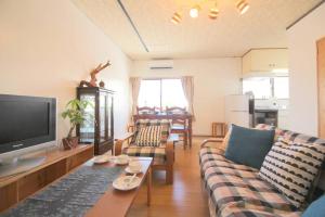 a living room with a couch and a tv at Beach side hotel YAMORIYANONIKAI J29 in Nago