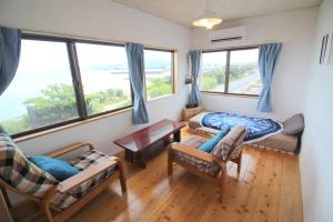 a living room with a couch and a bed and windows at Beach side hotel YAMORIYANONIKAI J29 in Nago