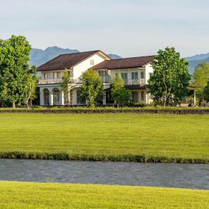 a large house with a grass field and a river at Deja Vu B&B in Dayi