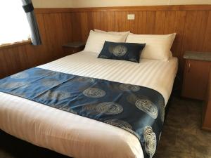 
a bed with a white comforter and pillows at Beechworth Lake Sambell Caravan Park in Beechworth
