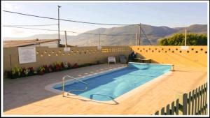 a swimming pool with a wooden floor and a wall at בחצר של טובה in H̱azon