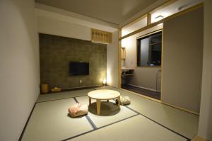 Kleines Zimmer mit einem Tisch und einem TV. in der Unterkunft Yufuin Tsuru no Yu in Yufu