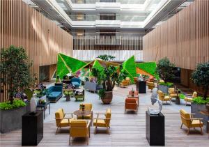 a lobby with chairs and tables and plants at 北京大悦酒店 in Beijing