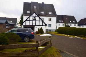 a car parked in front of a white house at FeWo Julie in Winterberg