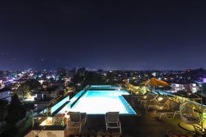 uma piscina com cadeiras e uma cidade à noite em Dahlia Boutique Hotel em Pokhara