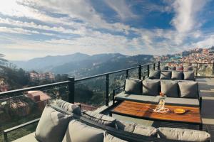 a balcony with couches and a table with a view at Hotel Willow Banks - Boutique 4 star Hotel on the Mall Road Shimla in Shimla