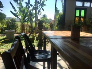 a wooden table and chairs with a view of a garden at Soluna Guest House in Pantai Cenang