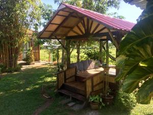 een houten pergola met een bank in een tuin bij Soluna Guest House in Pantai Cenang