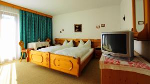 1 dormitorio con 1 cama y TV en Haus Geiger, en Scharnitz