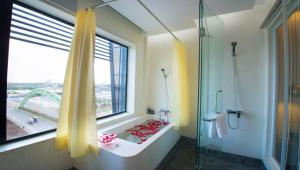 a bathroom with a shower and a window with a tub at Almond Hotel Bassac River in Phnom Penh +81 photos