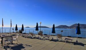 a group of chairs and umbrellas next to the water at Hotel San Terenzo in Lerici