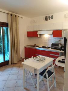 uma cozinha com armários vermelhos e uma mesa branca em Casa Luciano em Murta Maria