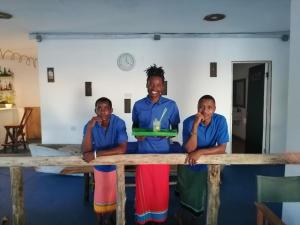 Eine Gruppe von drei Männern, die hinter einem Tisch stehen. in der Unterkunft Pemba Paradise in Makangale