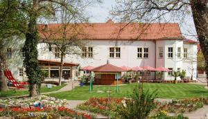 ein großes weißes Haus mit einem Hof mit Blumen in der Unterkunft Hotel Weidenmühle in Mühlhausen