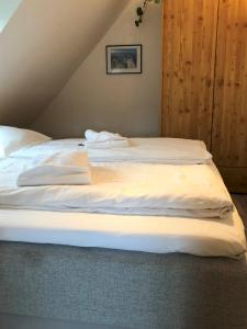 Una cama con sábanas blancas en un dormitorio en Haus Heidehof Whg. 14, en Cuxhaven