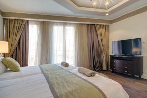 a bedroom with a large bed and a flat screen tv at Waldorf Astoria Residences- Rental Israel in Jerusalem