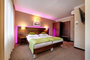 um quarto com uma cama grande e iluminação roxa em Hotel Leśny em Bialystok