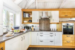eine Küche mit weißen Schränken und einer Arbeitsplatte in der Unterkunft Pear Tree Cottage in Newquay