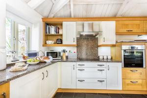 a kitchen with white cabinets and a counter top at Pear Tree Cottage in Newquay