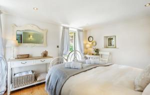 ein weißes Schlafzimmer mit einem Bett und einem Spiegel in der Unterkunft Pear Tree Cottage in Newquay