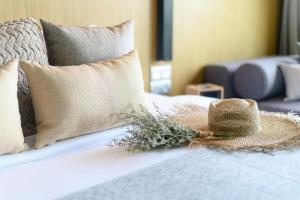 a straw hat sitting on a bed with a pillow at Wyndham Grand Nai Harn Beach Phuket in Nai Harn Beach