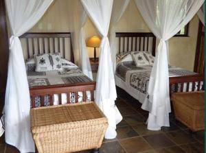 a bedroom with two beds with white drapes at Metsi Lodge in Welgevonden Game Reserve