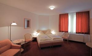 a bedroom with a bed and a couch and a table at Hotel Weidenmühle in Mühlhausen