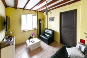 una sala de estar con una silla de cuero negro y una puerta en Gîte d’Anna, en Mackenheim