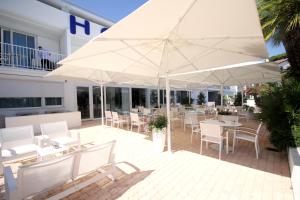 un patio con mesas blancas, sillas y sombrillas en Hôtel Josse, en Antibes