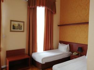 um quarto de hotel com duas camas e uma janela em Azcot Hotel em Baku