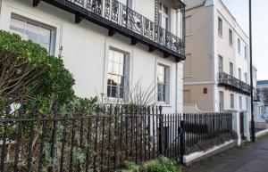 a white house with a wrought iron fence at Dale Street Apartments Suite in Leamington Spa