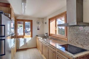 a kitchen with wooden cabinets and a sink and windows at Gaiola 1er in Bagnes