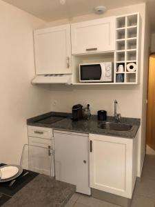 a kitchen with white cabinets and a sink and a microwave at Studio 104 in Mantes-la-Jolie
