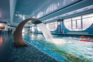 a pool with a water fountain in a building at Green Park in Domodedovo