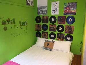 a green bedroom with a bed with records on the wall at HouseNandoor in Tainan