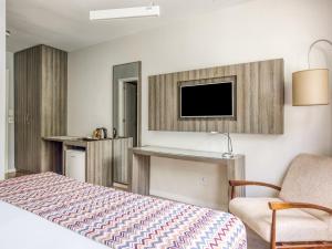 um quarto com uma cama, uma televisão e uma cadeira em CHA Pampulha Design Hotel em Belo Horizonte