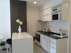a kitchen with white cabinets and a vase of flowers on a counter at La Suitte in Bahía Blanca