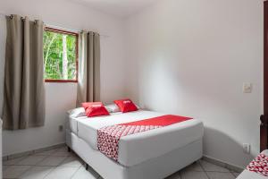 a white bed with red pillows in a room at OYO Pousada Tia Léo Campinas in Campinas