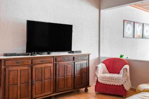 a living room with a tv and a red chair at OYO Pousada Tia Léo Campinas in Campinas