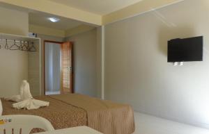 a bedroom with a bed and a flat screen tv on the wall at Lebanon Praia Hotel in Tramandaí