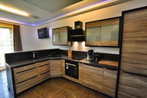 a kitchen with wooden cabinets and a black counter top at Home Apartments 17 in Kołobrzeg +14 photos