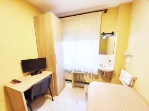 a small room with a bed and a desk with a television at Pensión Belmonte II in Benicarló +27 photos