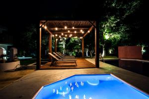 巴利亚多利德Hotel Boutique Casa Xaan的一个带椅子的凉亭和一个夜间游泳池